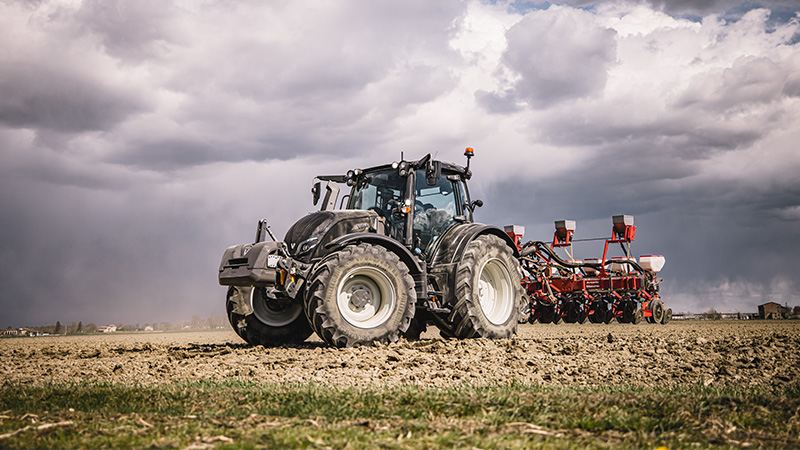Traktor der Valtra N-Serie in Schwarzmetallic mit Einzelkornsämaschine in der Frühjahrsbestellung.