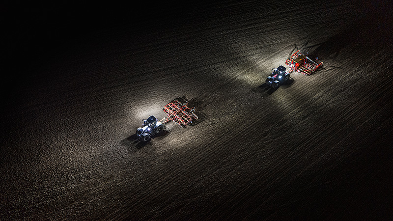 2 Traktoren der Valtra Q-Serie bei Bodenbearbeitung nachts mit Arbeitsbeleuchtung